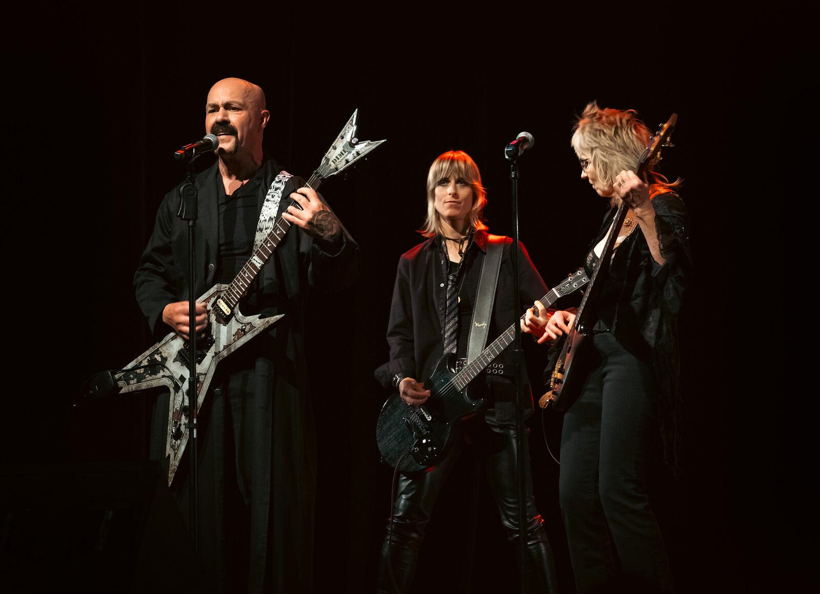 Dark Ballet no palco, com três músicos tocando guitarras e baixo