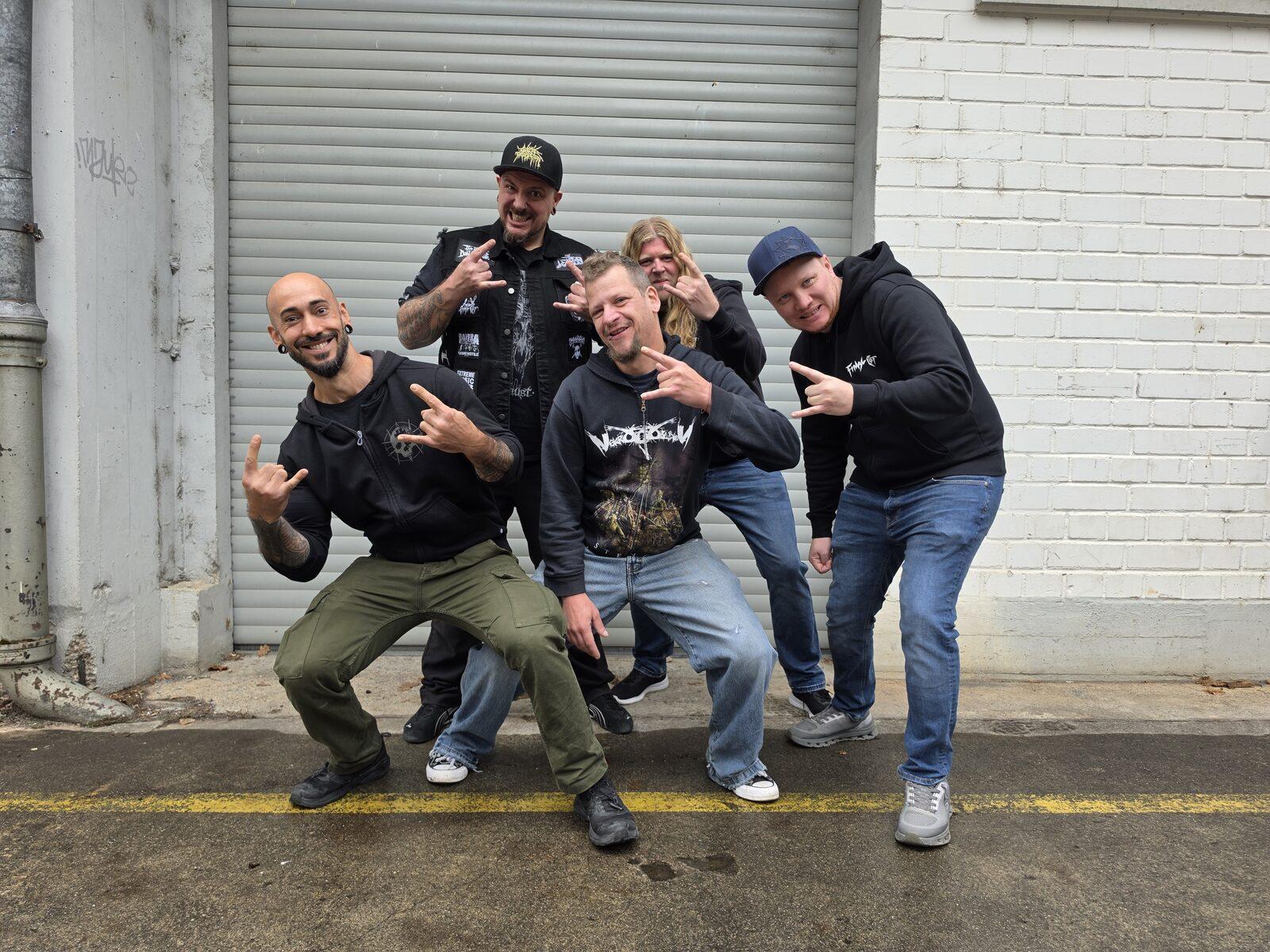 Os cinco integrantes da Final Cut posando numa rua em frente a portões de garagem