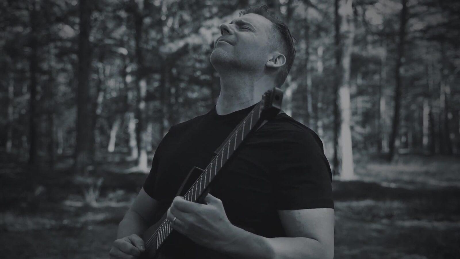 Guitarrista do Odjur tocando numa floresta, em cena do clipe de Never Alone